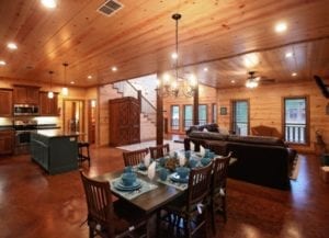 The large great room and kitchen, all wood paneled with wood floors.
