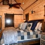 The king bed in one of the master suites with a cozy looking plaid comforter.