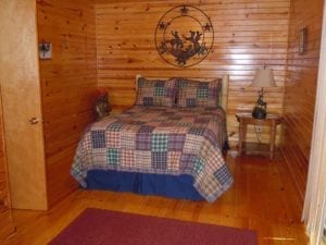 One of the wood-paneled bedrooms showing a bed with a plain quilt.
