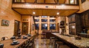 The kitchen with an island and chairs on the right side and a long farm-type table with chairs on the left.