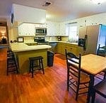 Picture of the large kitchen showing the island and a small hightop table.