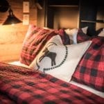 Bed covered in red plaid comforter in a wood-paneled bedroom