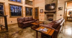 Lounge area with brown leather sofas and a TV over the fireplace.