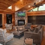 The sitting are with a brown sofa and chairs, fireplace and TV.