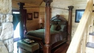 A bedroom with a large 4-poster wood bed.