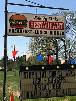 Shady Oaks Restaurant sign. Text: Breakfast, Lunch, Dinner, Stop and try our CF Stks, fish, burgers, Great BBQ, Daily Specials.