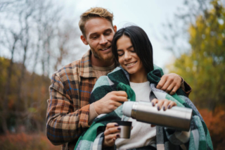 A couple enjoying coffee by the river, one of the creative date ideas to enjoy in Hochatown.